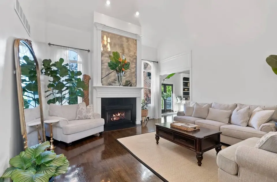 Living room before: gray sectional, TV above the fireplace, sparse walls